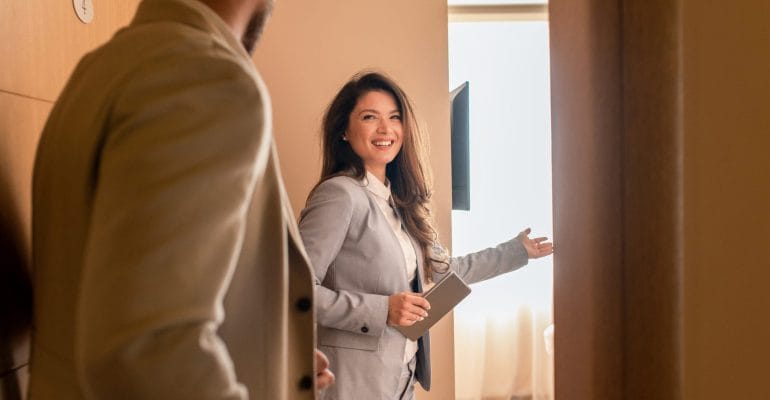 Young businessman check-in in hotel, smiling female receptionist  showing him available rooms.