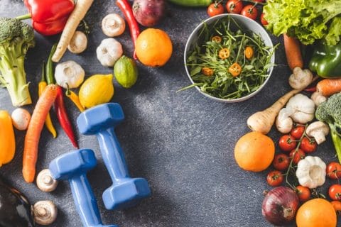 Female dumbbells and vegetables isolated on dark background